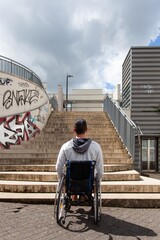 man in wheelchair looking at stairs