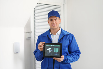 Worker with tablet computer checking alarm system indoors