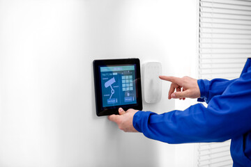 Worker with tablet computer checking alarm system indoors