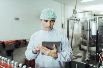 Male factory worker using digital tablet at drinks production factory.  concept inspecting production
