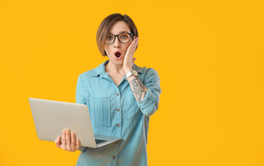 Shocked female programmer with laptop on color background