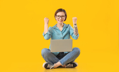 Happy female programmer with laptop on color background