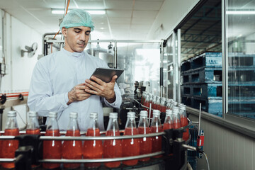 Male factory worker using digital tablet at drinks production factory.  concept inspecting production