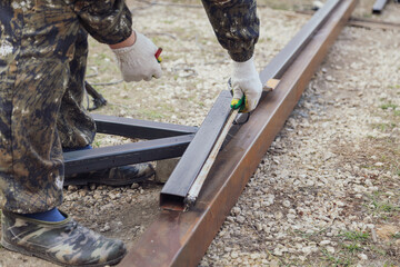 A worker makes a metal frame for a sliding gate.