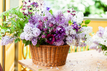 Beautiful bouquet of seasonal garden flowers in a wooden basket. Countryside house terrace.