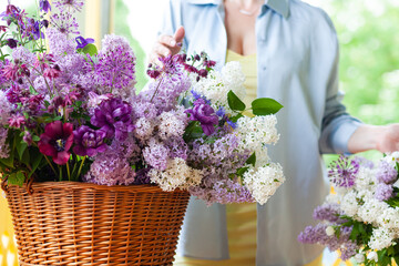 Beautiful woman florist making fresh spring bouquet with purple lilacs. Close up, faceless