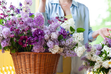 Beautiful woman florist making fresh spring bouquet with purple lilacs. Close up, faceless