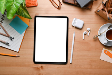 Top view mock up digital tablet, stylus pen, earphone, notebook and stationery on wooden table.