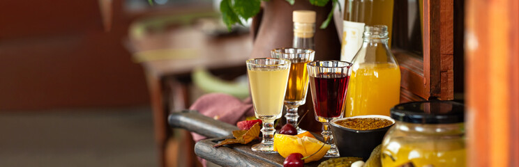 Traditional russian drinks: strong alcohol in small shot glasses with natural berries, lemon. Served on wooden board with appetizers for aperitif. Colorful still-life, delicious food. Close up
