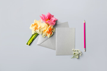 Beautiful flowers and blank card with envelope on light background