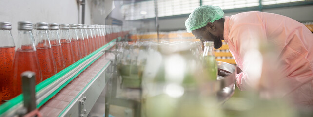 African american worker inspecting production line at drinks production factory. working Concept