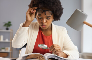 Surprised inquisitive black woman with magnifying glass takes off glasses as she sees an amazing...