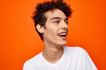 cute guy in white t-shirt and fun emotions close-up orange background