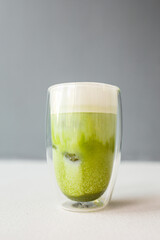 Matcha green tea with ice cubes on the grey background
