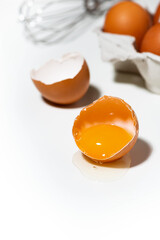 broken chicken egg on white background, baking ingredients, vertical
