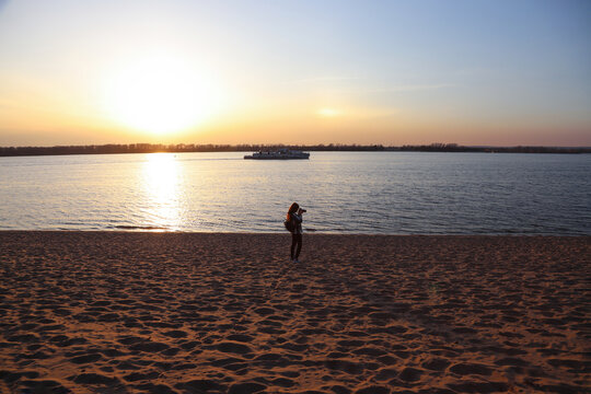 Girl takes photos on a beach at sunset or sunrise
