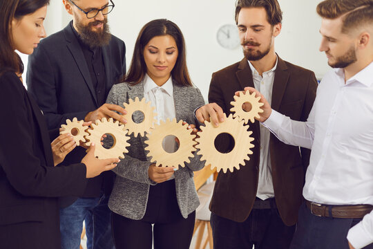 Young company managers joining gearwheels as metaphor for effective management and collaboration