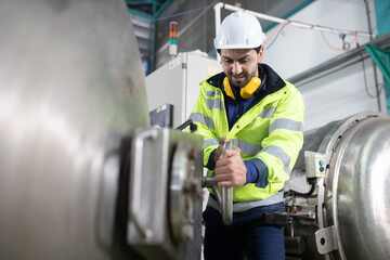 workers inspecting pressure valves on a tank. The worker is closing the pressu