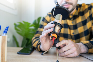 hands holding a microphone while recording a podcast