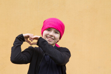 portrait of smiling girl with headscarf and making heart symbol with hands