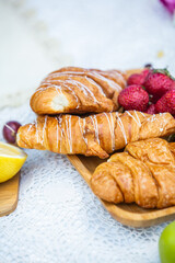 Outdoors picnic in a lush green park with a tasty croissant, fruits, donuts and wine on grass. Summer picnic on the blanket.