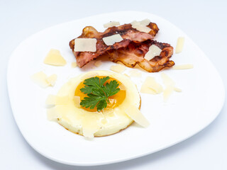 fried bacon strips and fried egg with cheese flakes over
