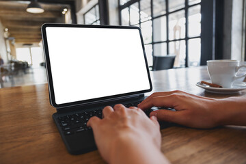 Mockup image of a woman using and typing on digital tablet with blank white desktop screen in cafe