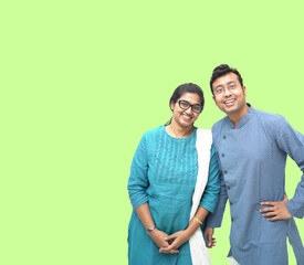 A closeup shot of a smiling Bengali couple in traditional ethnic clothes on a green background