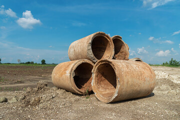 Old concrete pipes,  deteriorated sewer pipes are left or placed on the ground,  blue sky  background