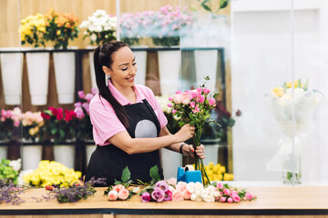 An attractive young female florist works in a flower shop and makes flower arrangements for sale