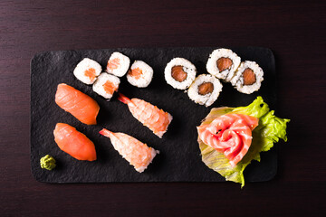 mixed sushi on black tray. top view, dark wooden background