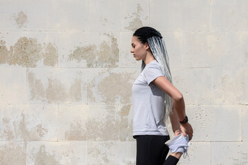 Fitness sport woman with african braids doing stretching exercise over gray wall