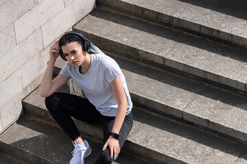 Woman listening music in city street. Sport activities on street and music