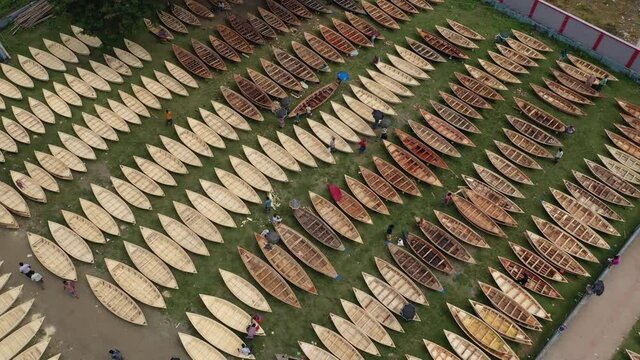 Aerial view of a few people working on repairing small wooden fishing boats in Ghior Central playground, Ghior, Dhaka, Bangladesh.