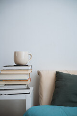 Fototapeta na wymiar coffee cup tea mug on stack of books next to a bed. White background front view