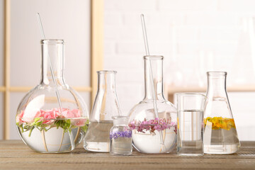 Laboratory glassware with flowers on wooden table. Extracting essential oil for perfumery and...