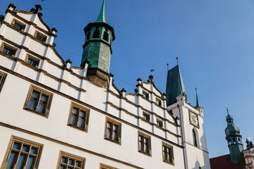 Renaissance building of regional museum, White Stone bell tower with clock near All Saints Church on main Peace Square, copper turret on roof, sunny day, Litomerice, Czech Republic