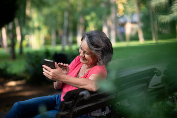 Senior woman using mobile phone in park.