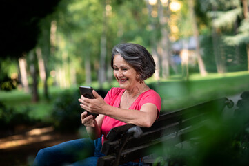 Senior woman using mobile phone in park.