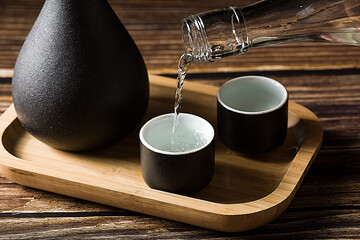 chinese liquor is poured into a ceramic cup on wood background