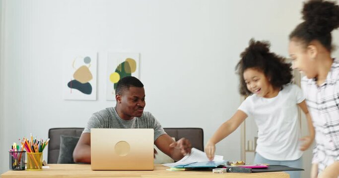 Happy girls bothering working black father at home