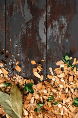 Frame from wood chips for smoking on a dark wood background top view. Copy space for text. Wood chips for smoking fish or meat, flat lay.
