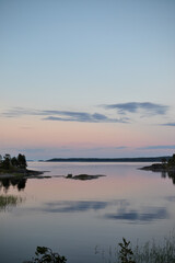 Fototapeta premium Evening nature at sunset, sunset lake view from the island, green grass and quiet lake, wilderness recreation and tourism, solitude, natural beauty for relaxation and enjoyment, island vacations and