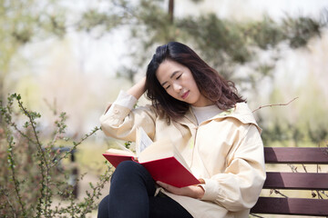 Female reading on bench in spring park