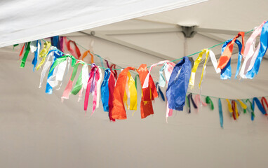 colorful ribbons tied to a rope, in a white tent, outside. Trade, holidays, decoration, colored ribbons, City Day.
