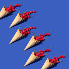 Creative pattern made with bright red cherries and ice cream cone on pastel purple background. Spring or summer fruit idea. Trendy summer fruit concept.