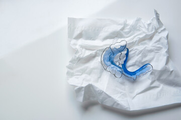 Closeup Blue retainer wrapping in a creased tissue on table with isolated white background with copy or negative space. healthcare concept