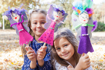 Two little girl playing with handmade dolls in park