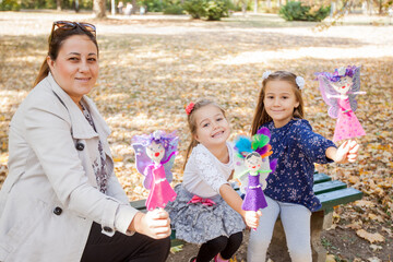 Happy family, mother with two daughters playing with handmade dolls