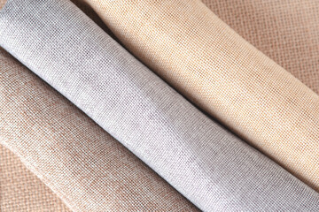 Natural fabrics from organic colors of flax and cotton in rolls, homespun textile handmade. Heap of cloth fabric.